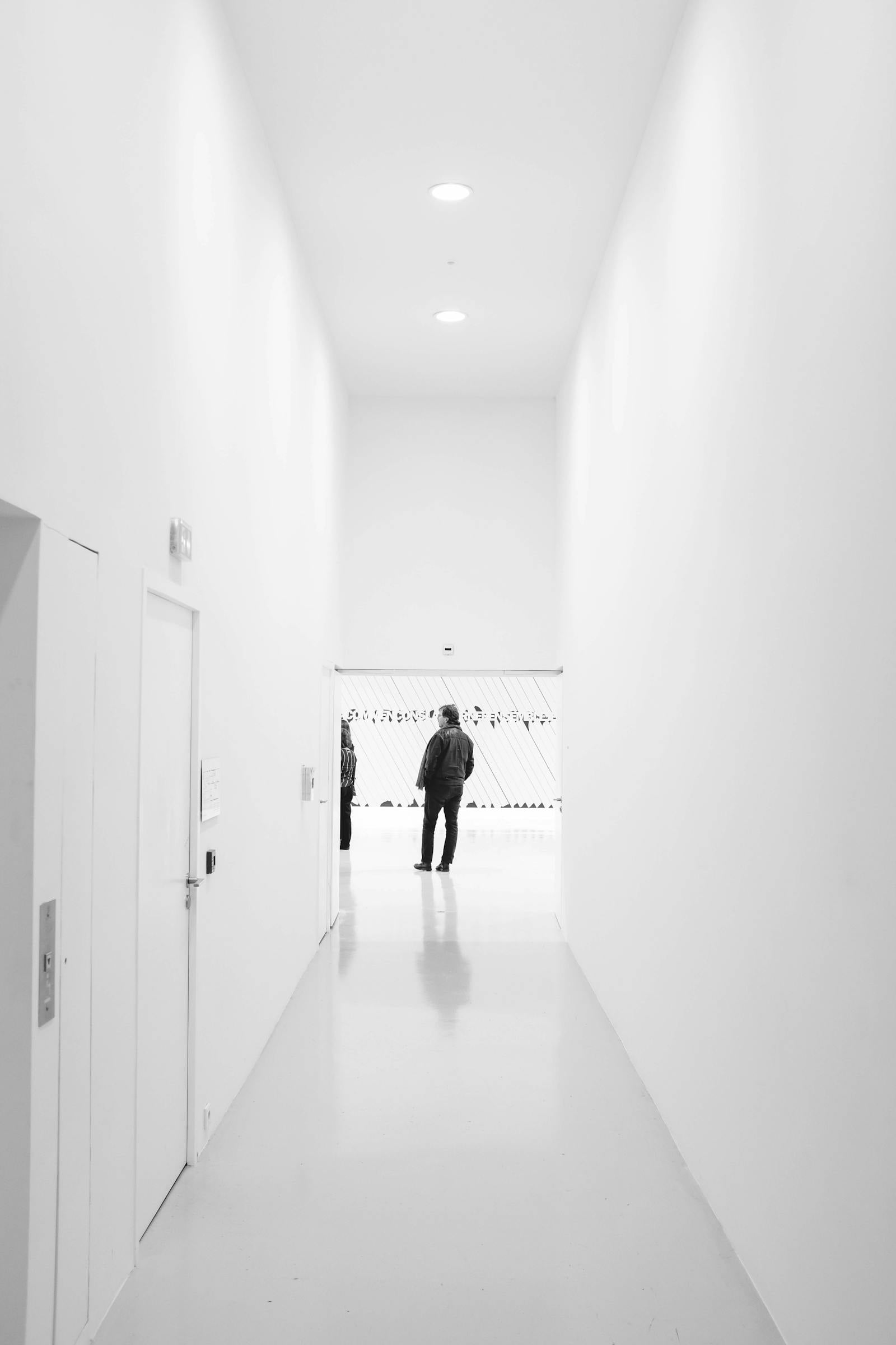 A lone figure in a bright minimalist gallery
